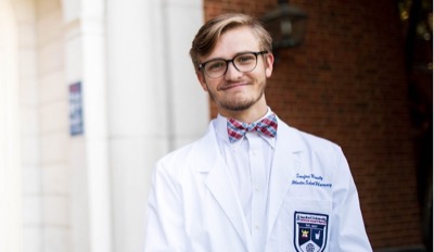 male student poses wearing labcoat